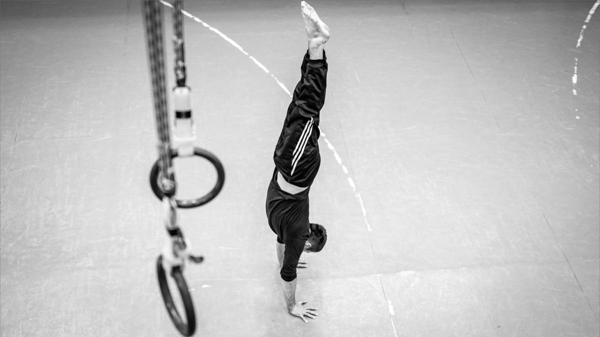 Athlete balancing in a handstand on a gym floor